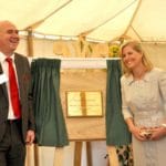 Sophie, Duchess of Edinburgh (formerly Countess of Wessex) and a man in a suit smiling beside an unveiled brass plaque on an easel.