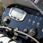 Custom motorcycle dashboard featuring a Trail Tech Vapor digital gauge, ignition switch, LED indicator lights, and a BMW logo.